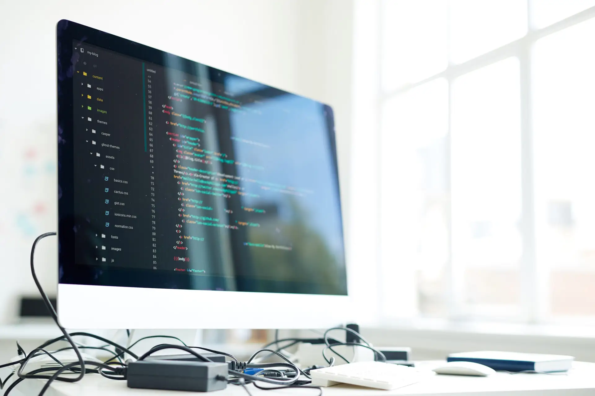 Computer screen showing lines of code beside an office window