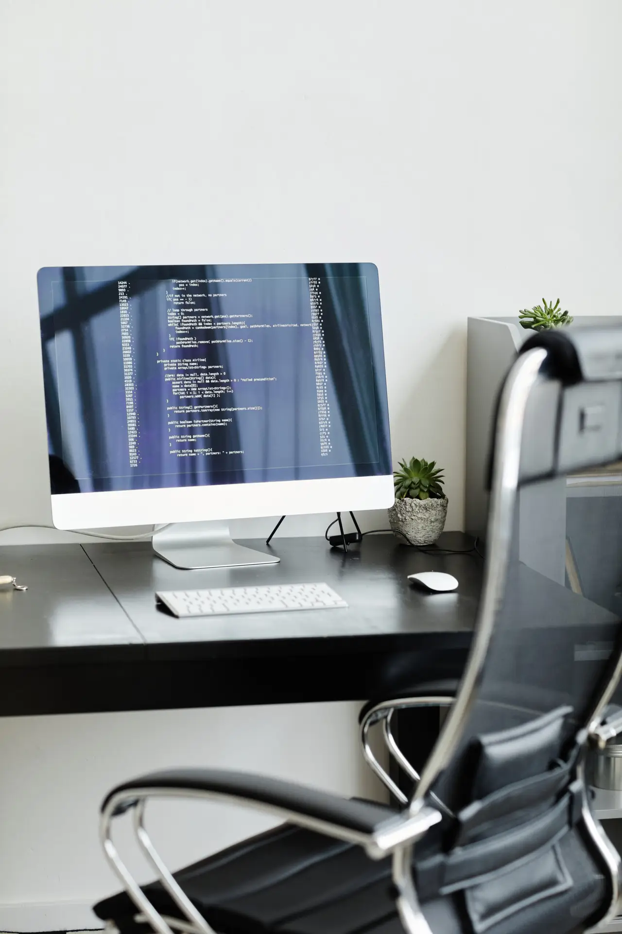 Desktop computer on an office desk displaying lines of code